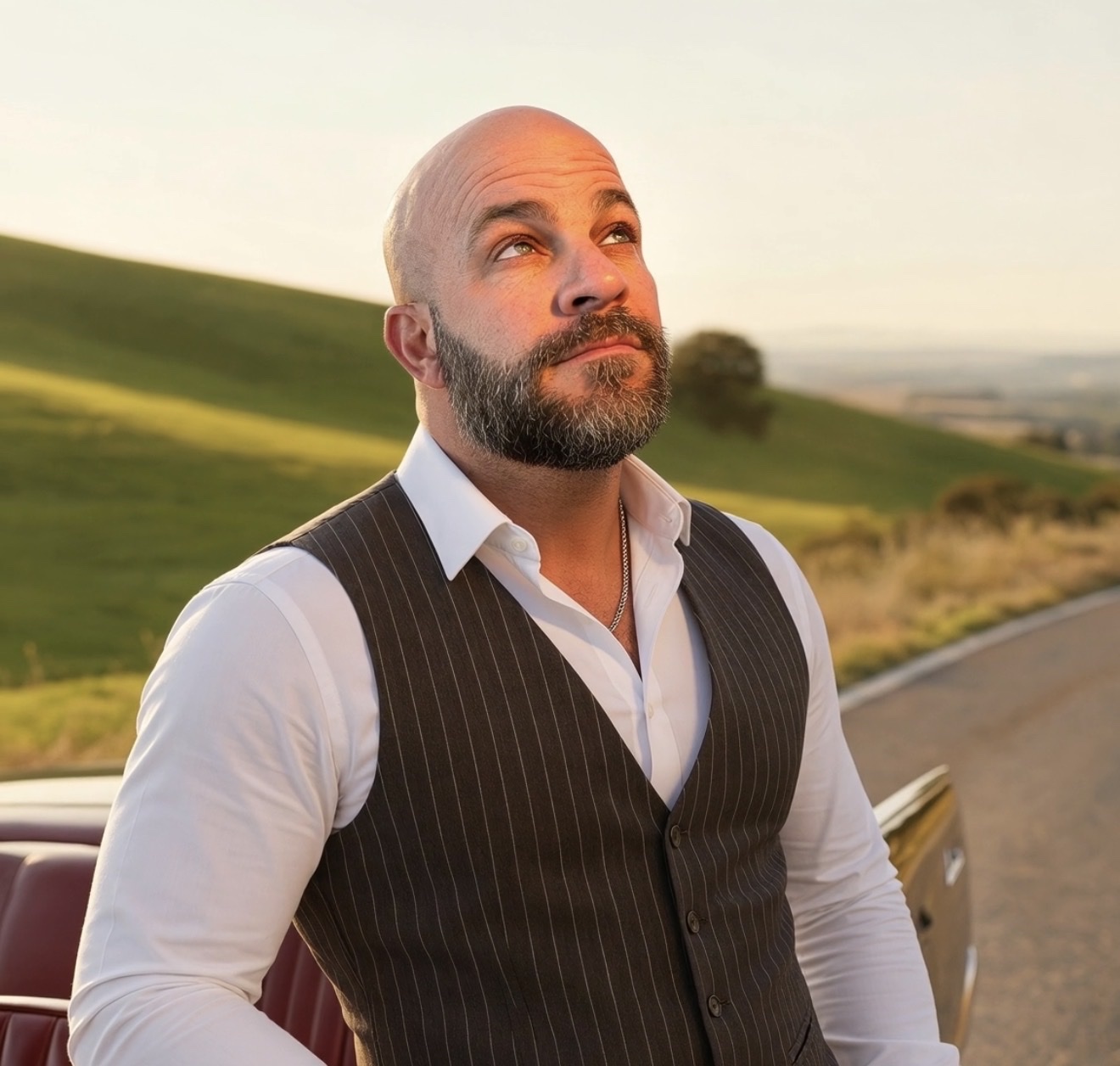 Matthew Young in professional attire beside a classic car at golden hour